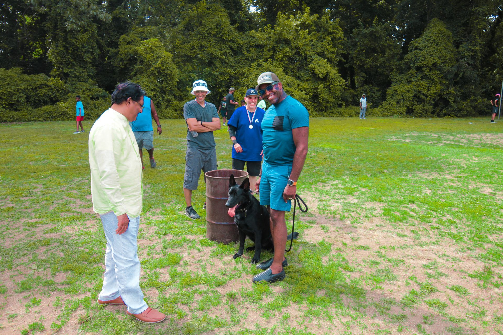 A group of people are standing in a grassy field with a dog.