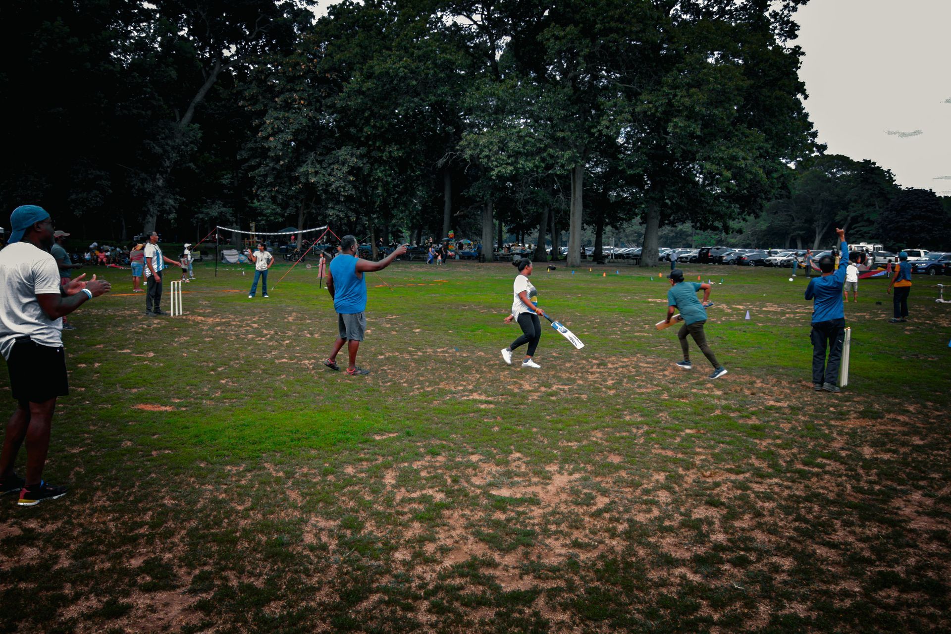 A group of people are playing cricket in a field.