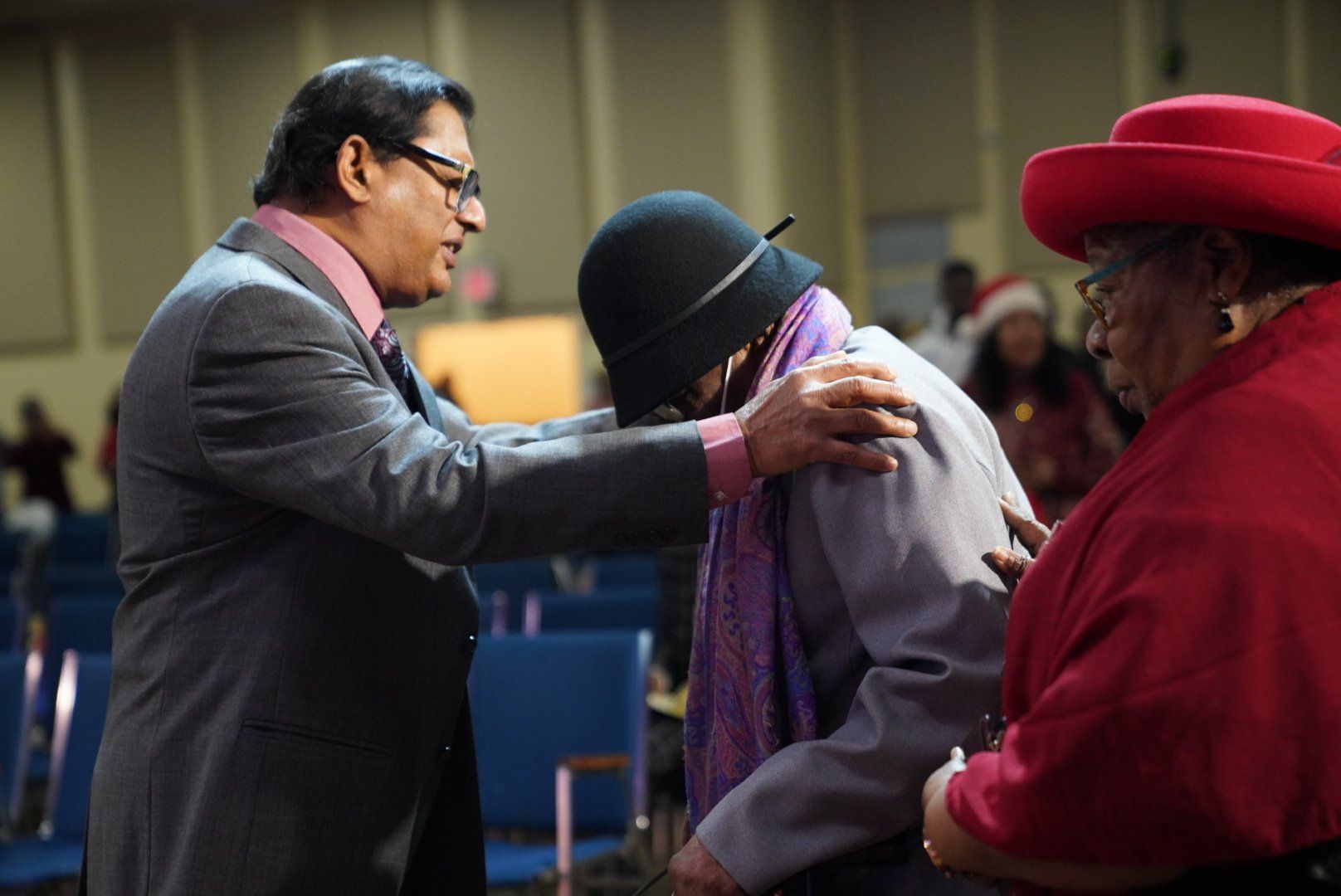 A man in a suit and tie is talking to a woman in a red hat.