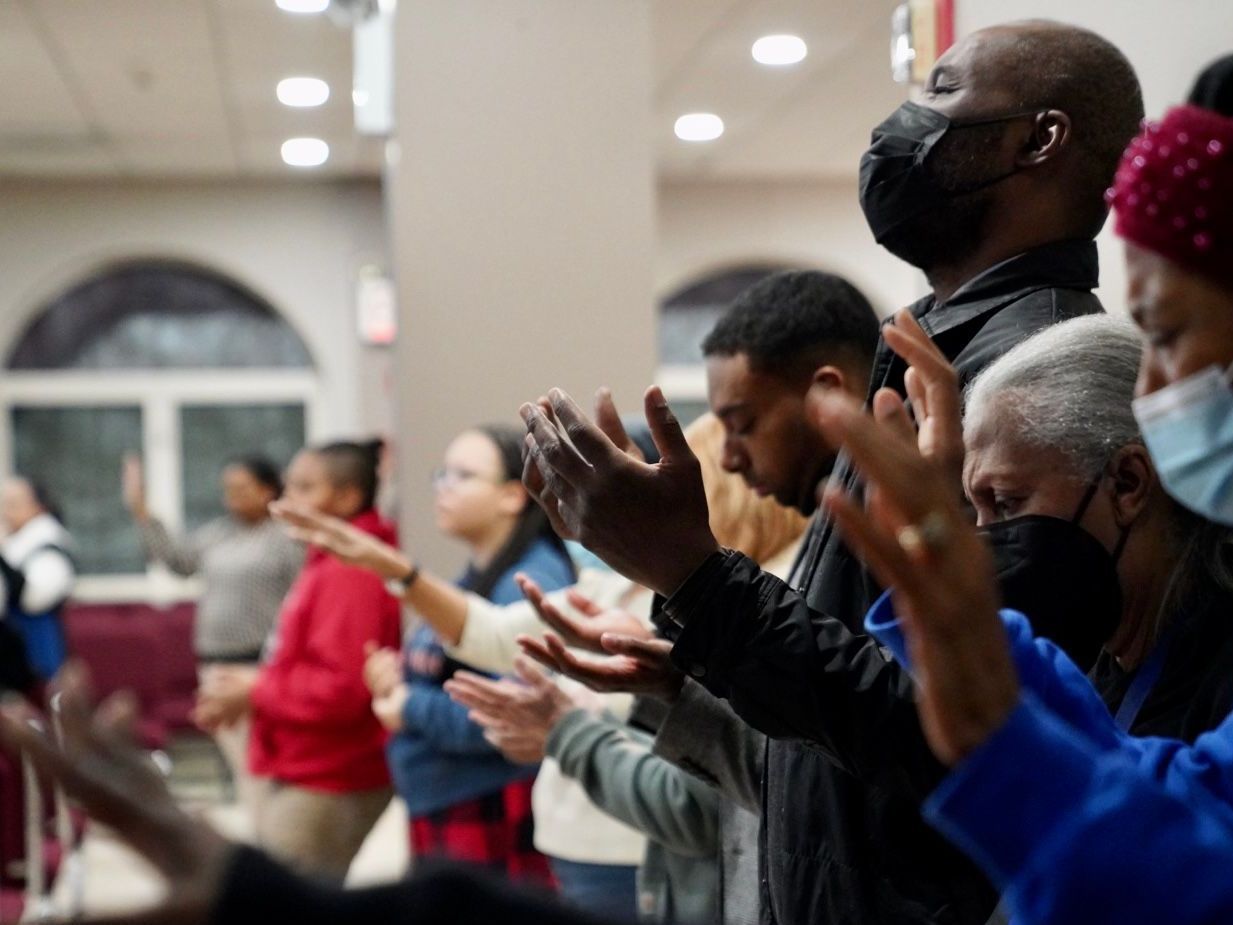 A group of people are standing in a room with their hands in the air.