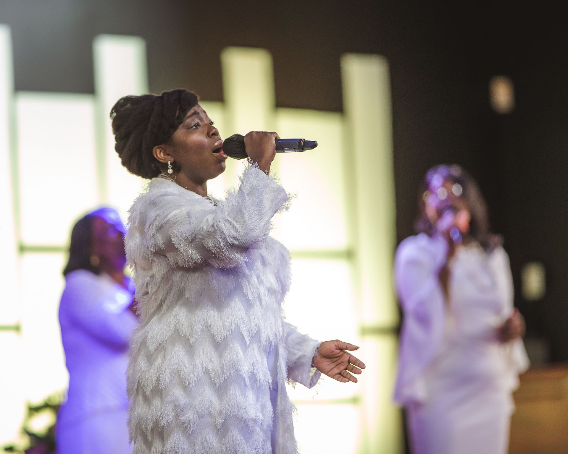 A woman in a white dress is singing into a microphone.