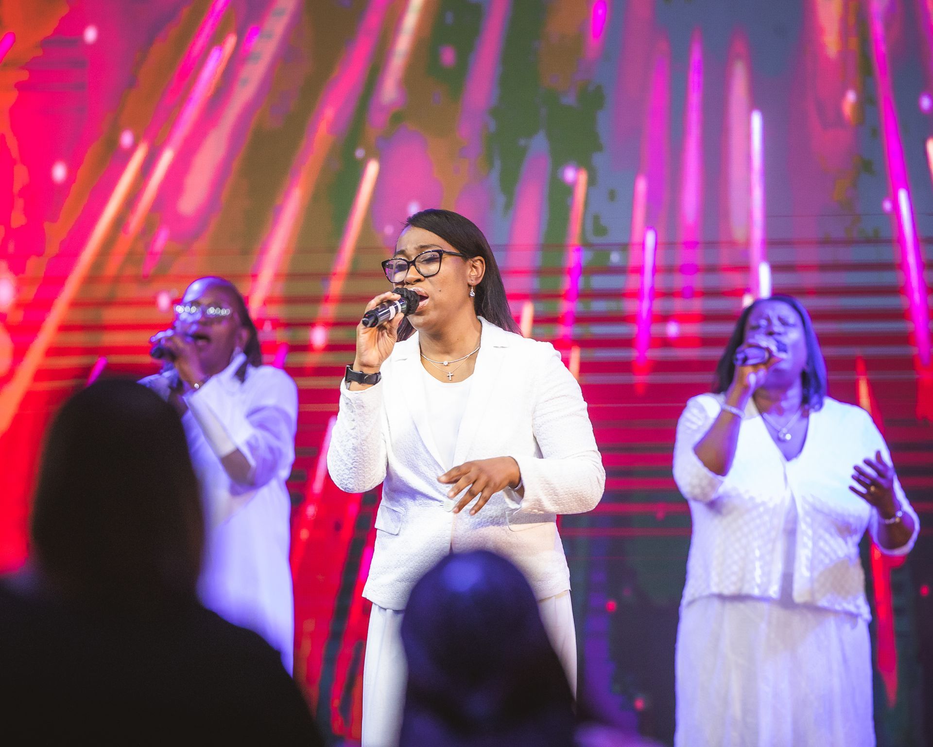 A group of women are singing into microphones on a stage.