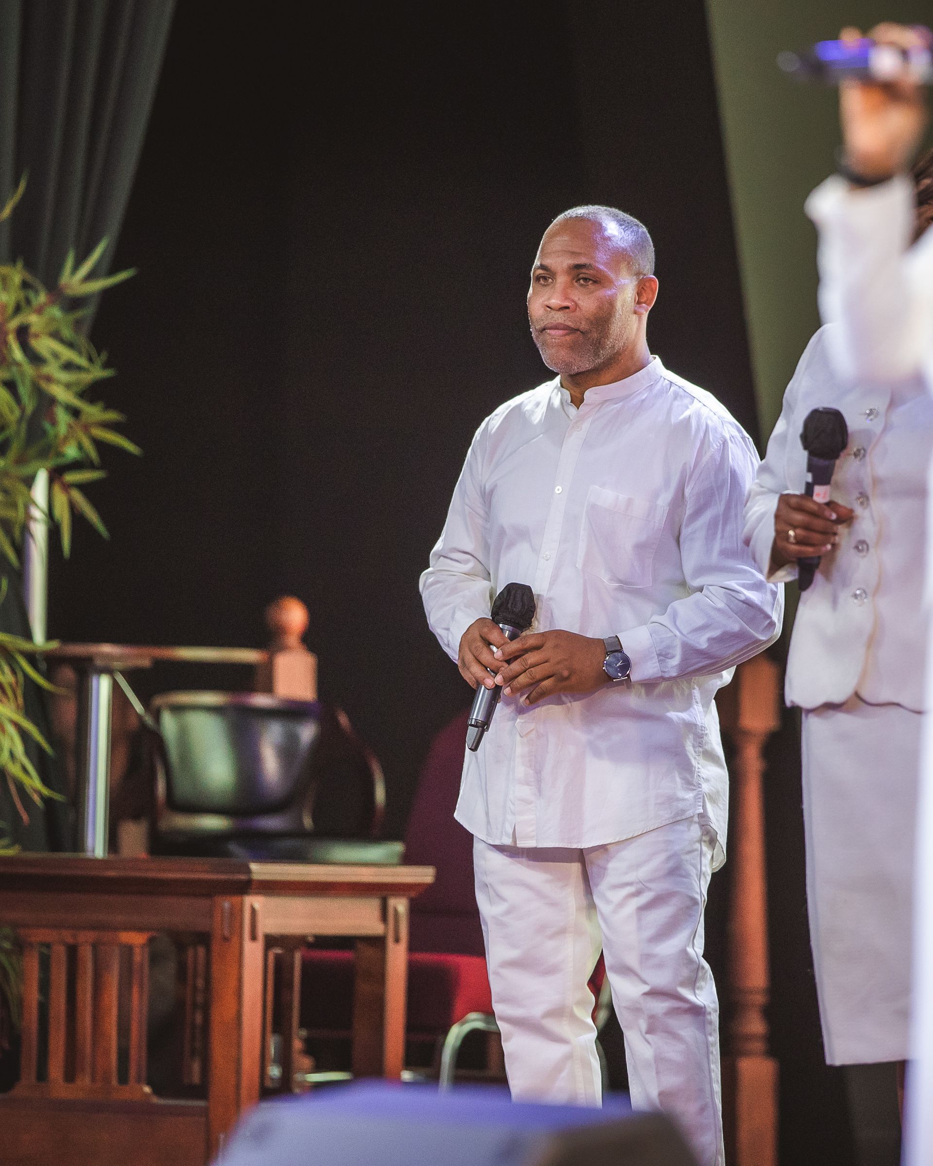 A man in a white shirt is holding two microphones