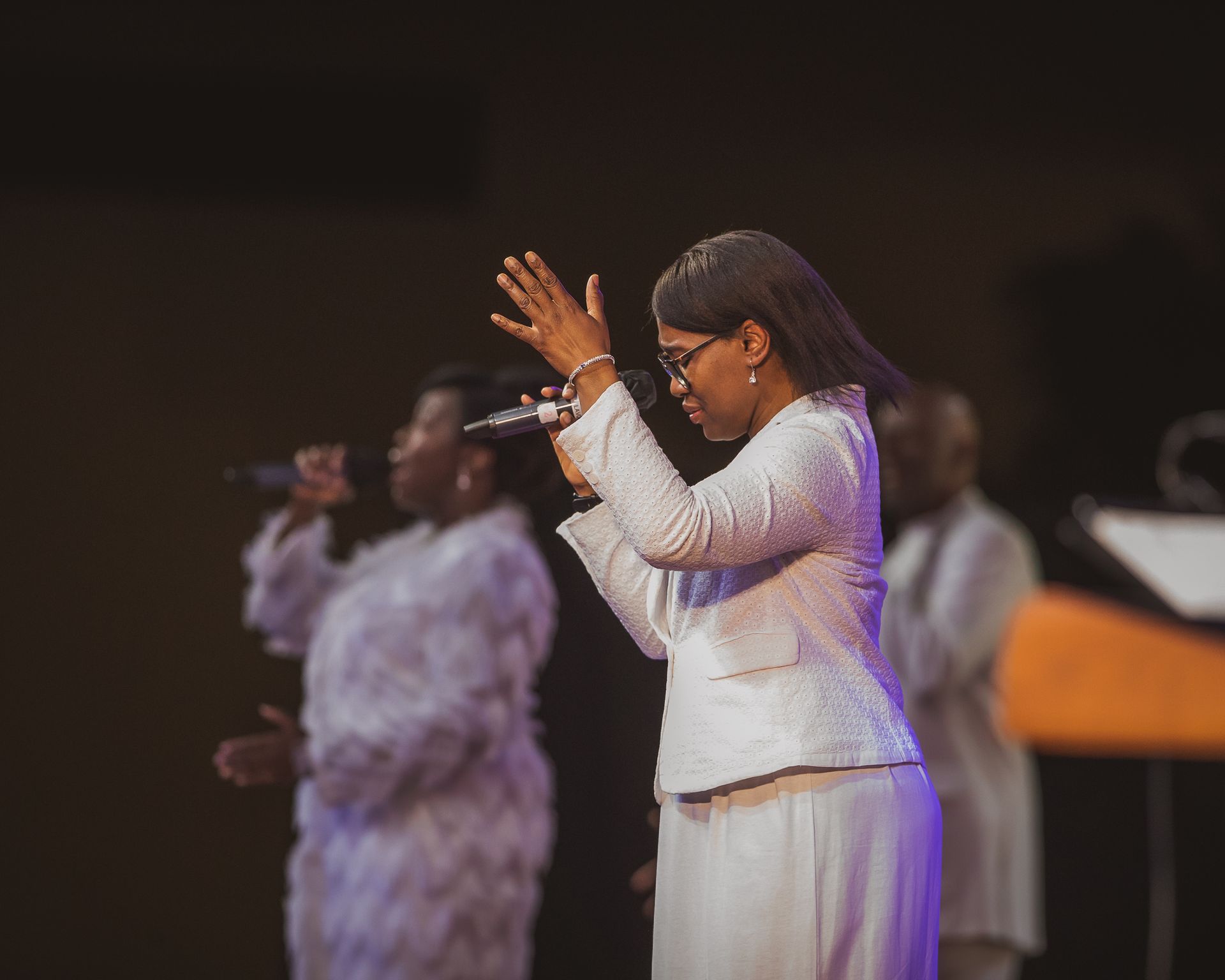 A group of women are singing into microphones on a stage.