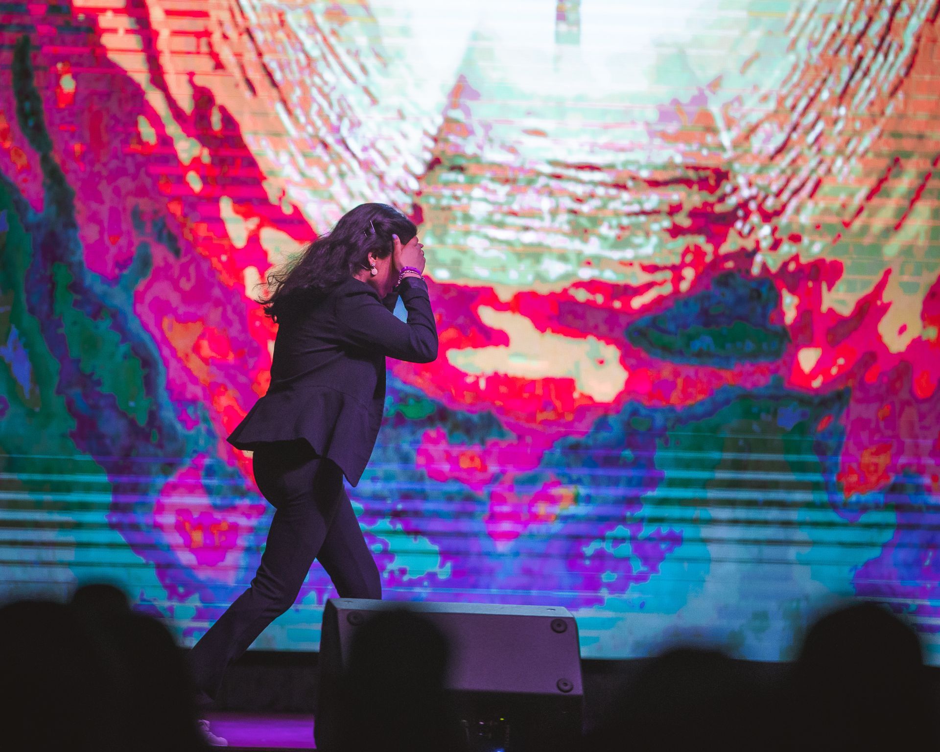 A man is singing into a microphone on a stage in front of a crowd.