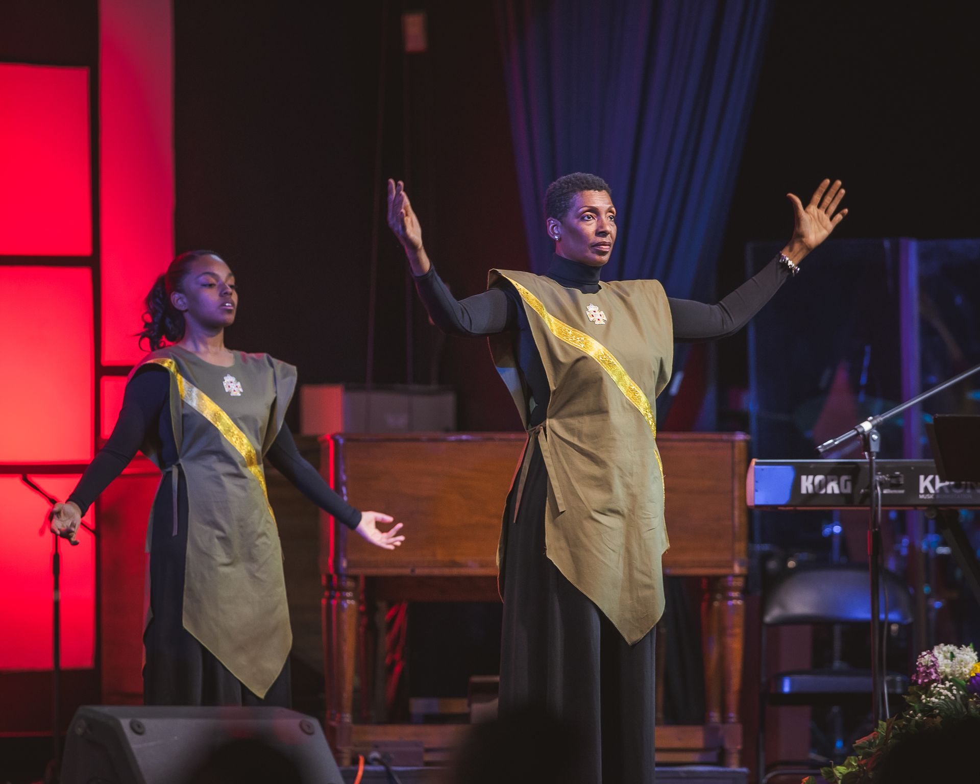 Two people are standing on a stage with their arms outstretched.