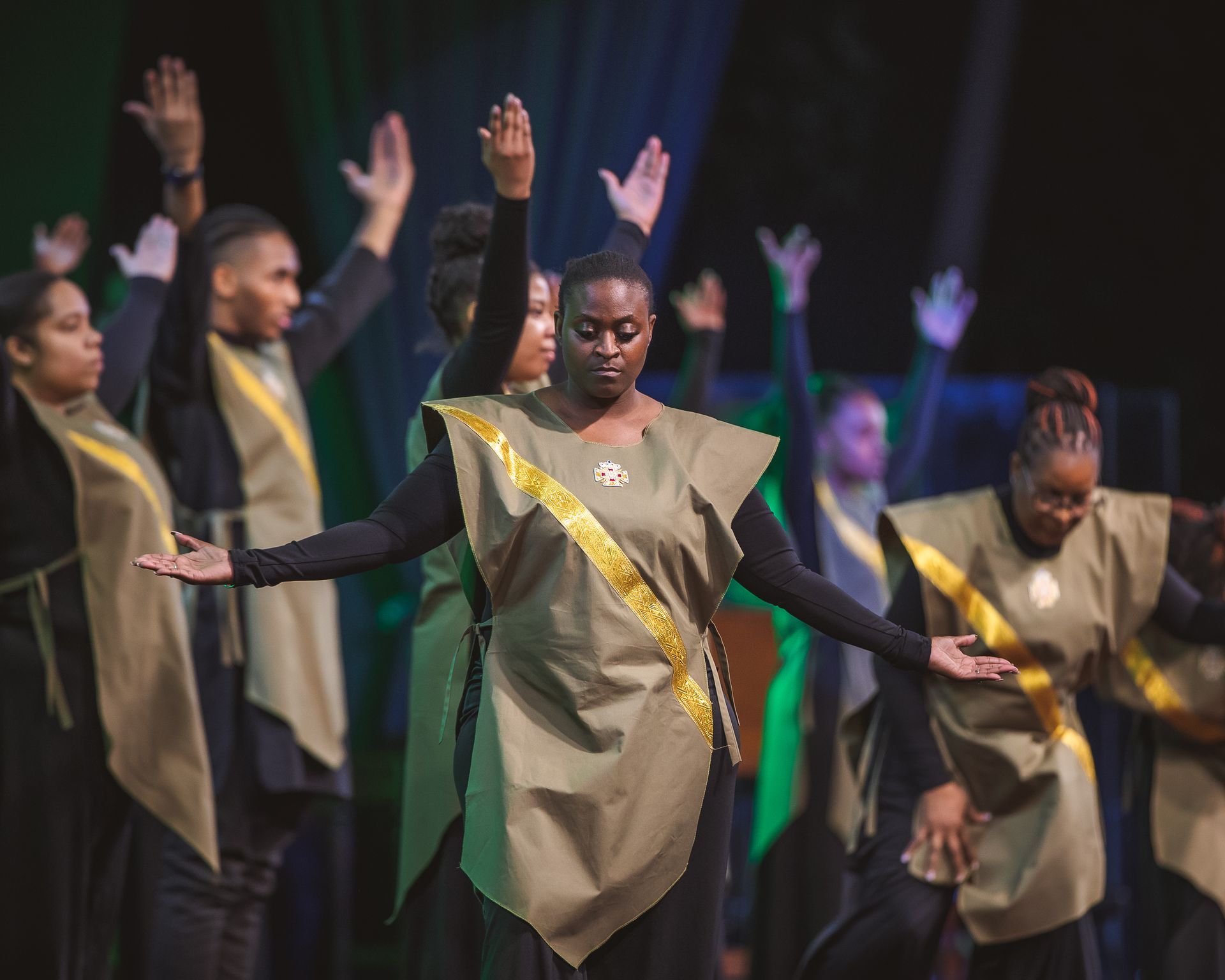 A group of people are dancing on a stage with their hands in the air.