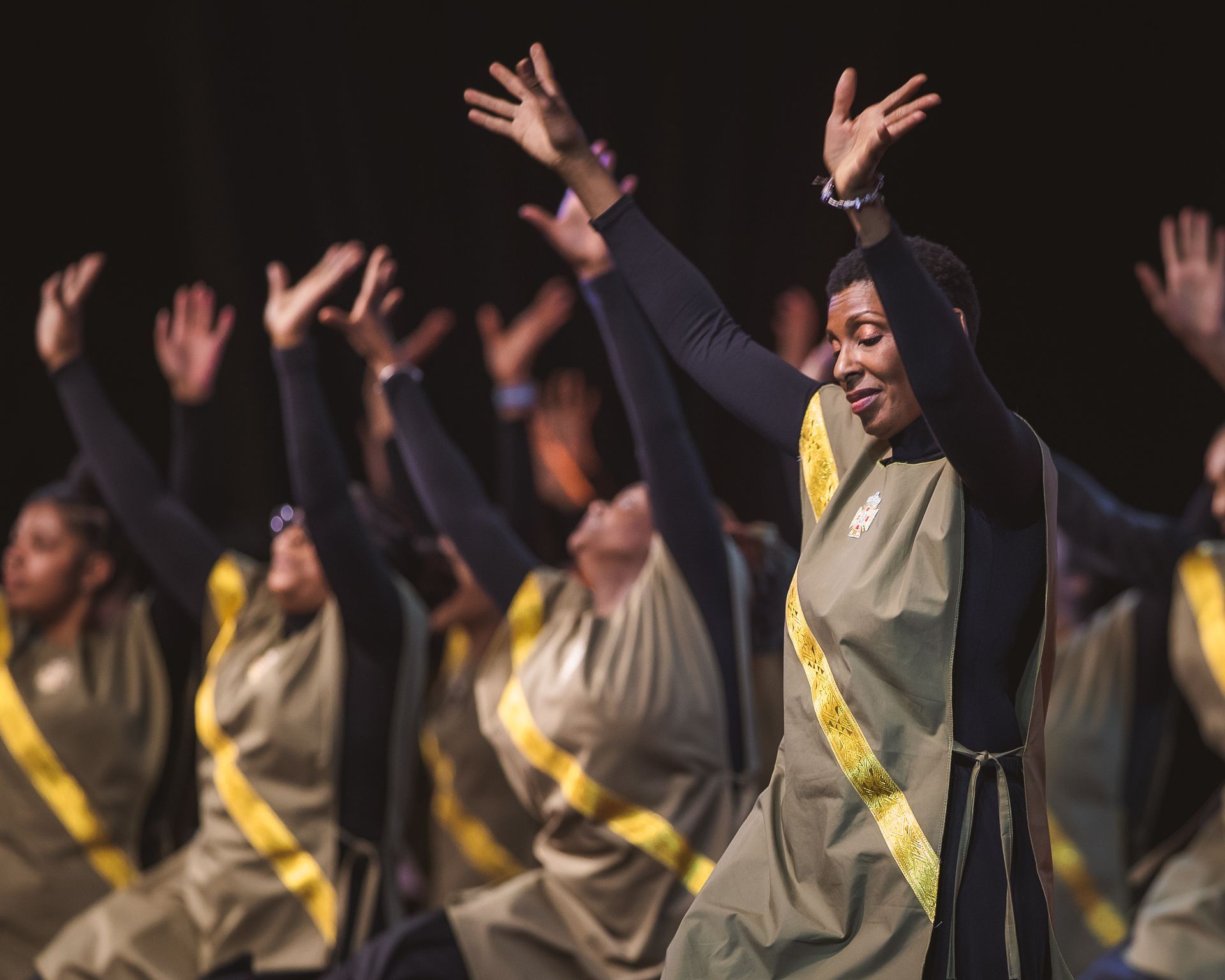 A group of people are dancing with their arms in the air.