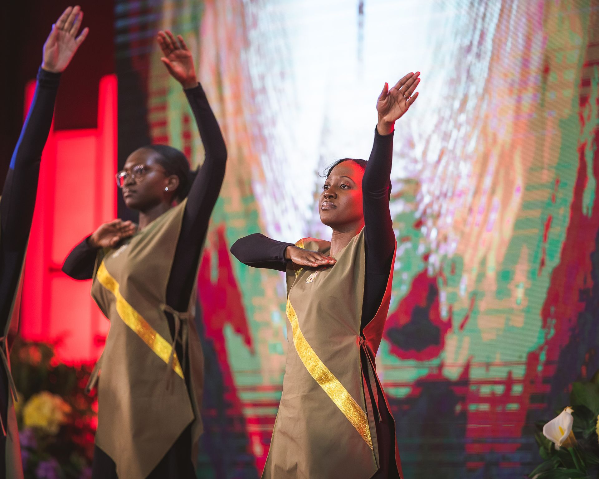 A group of women are dancing on a stage with their arms in the air.