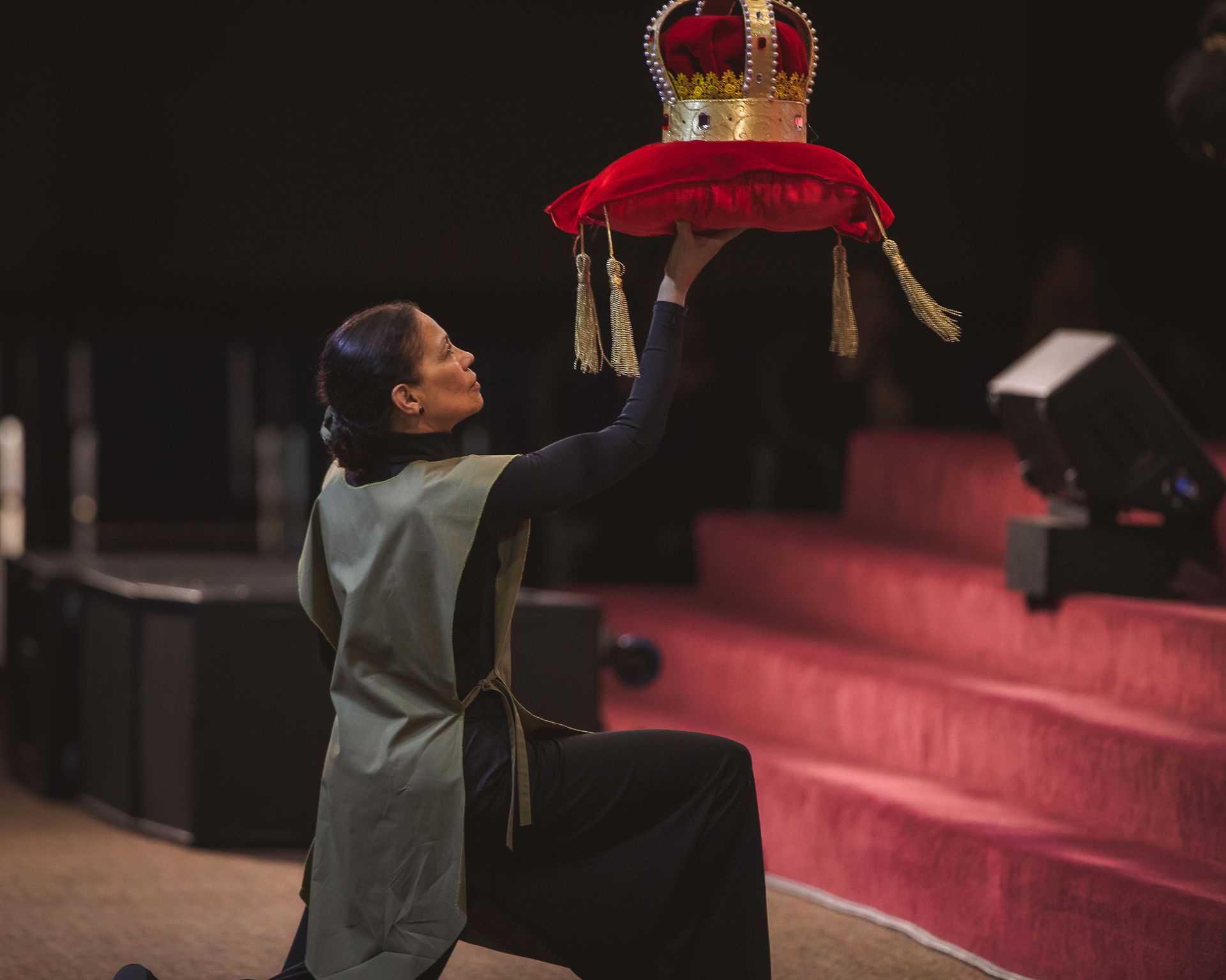 A woman is holding a red pillow with a crown on it