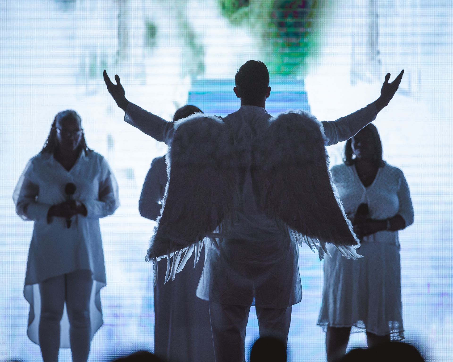 A man with angel wings is standing in front of a group of people.