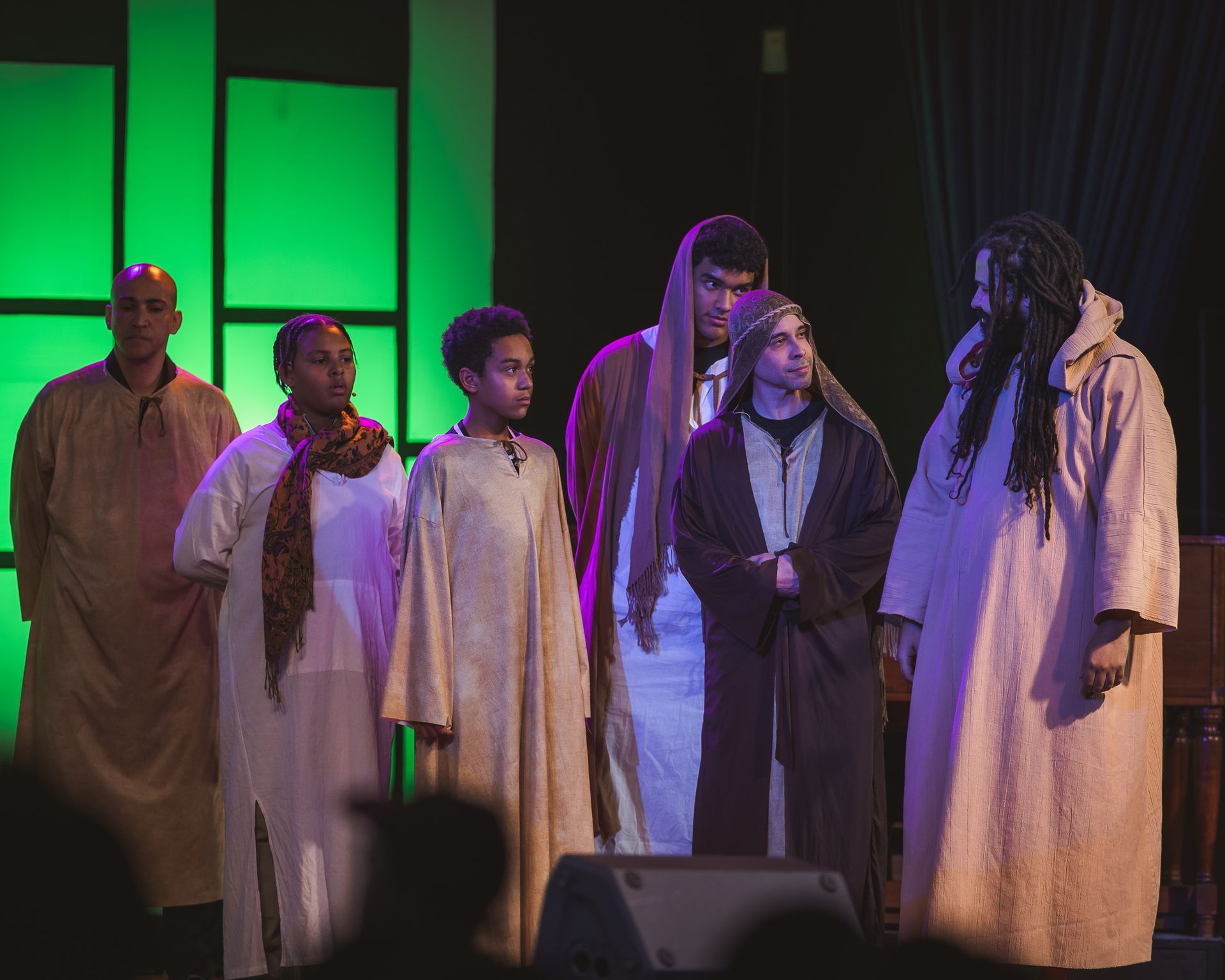 A group of people are standing on a stage in front of a microphone.