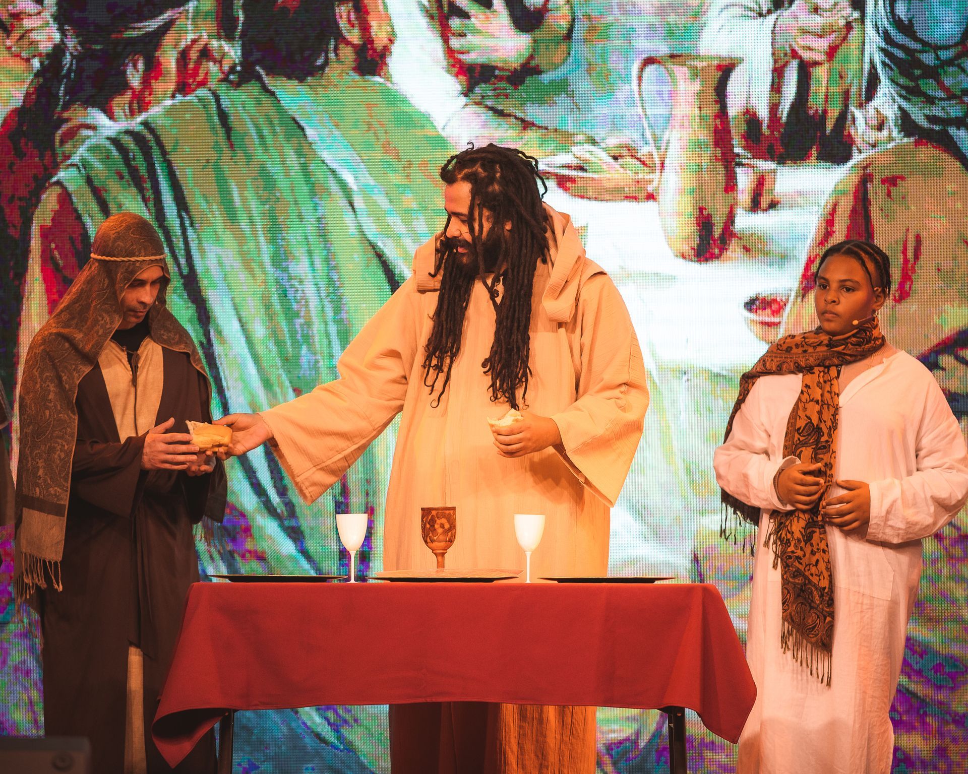 A group of people are standing around a table in front of a large screen.