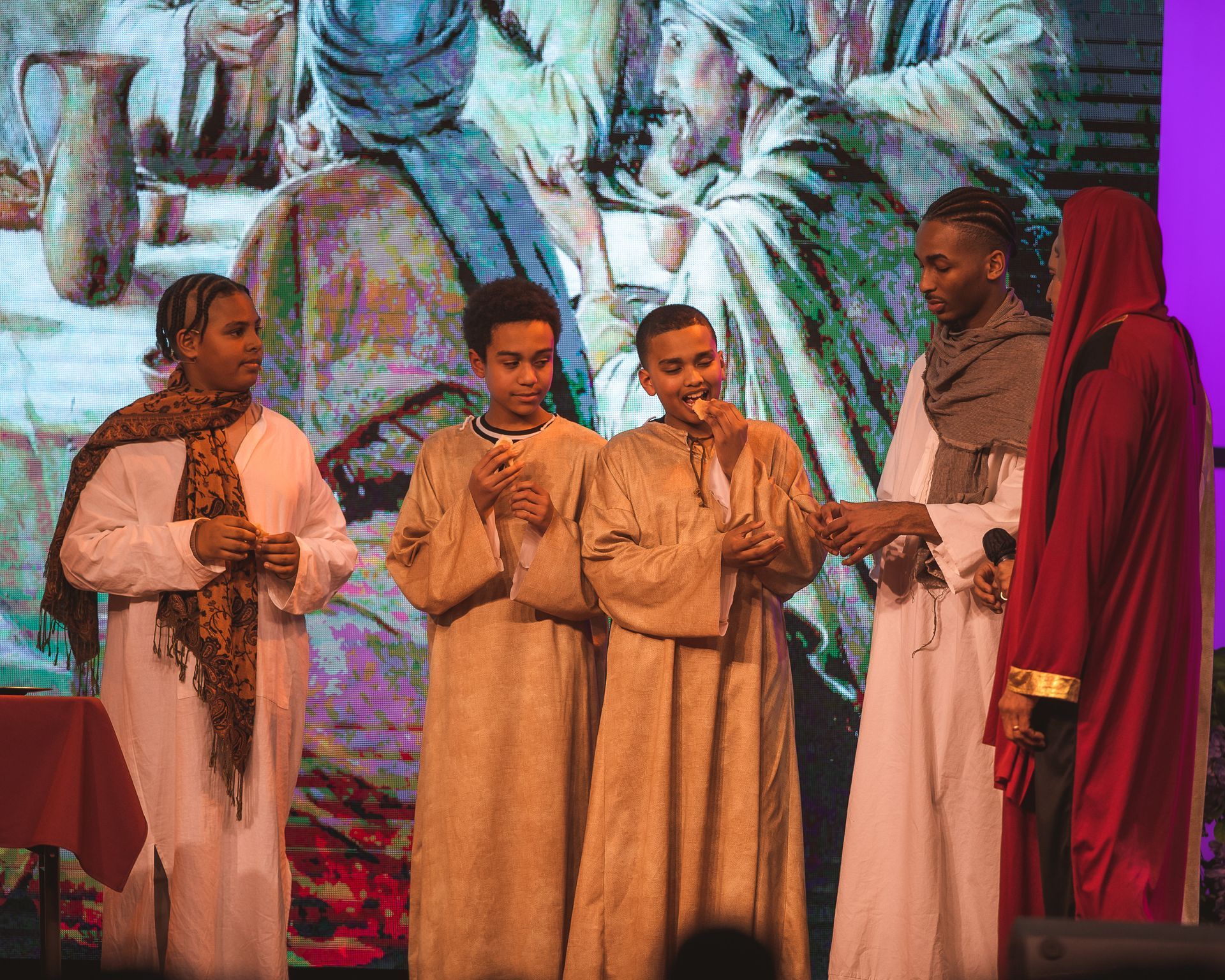 A group of people are standing on a stage in front of a large screen.