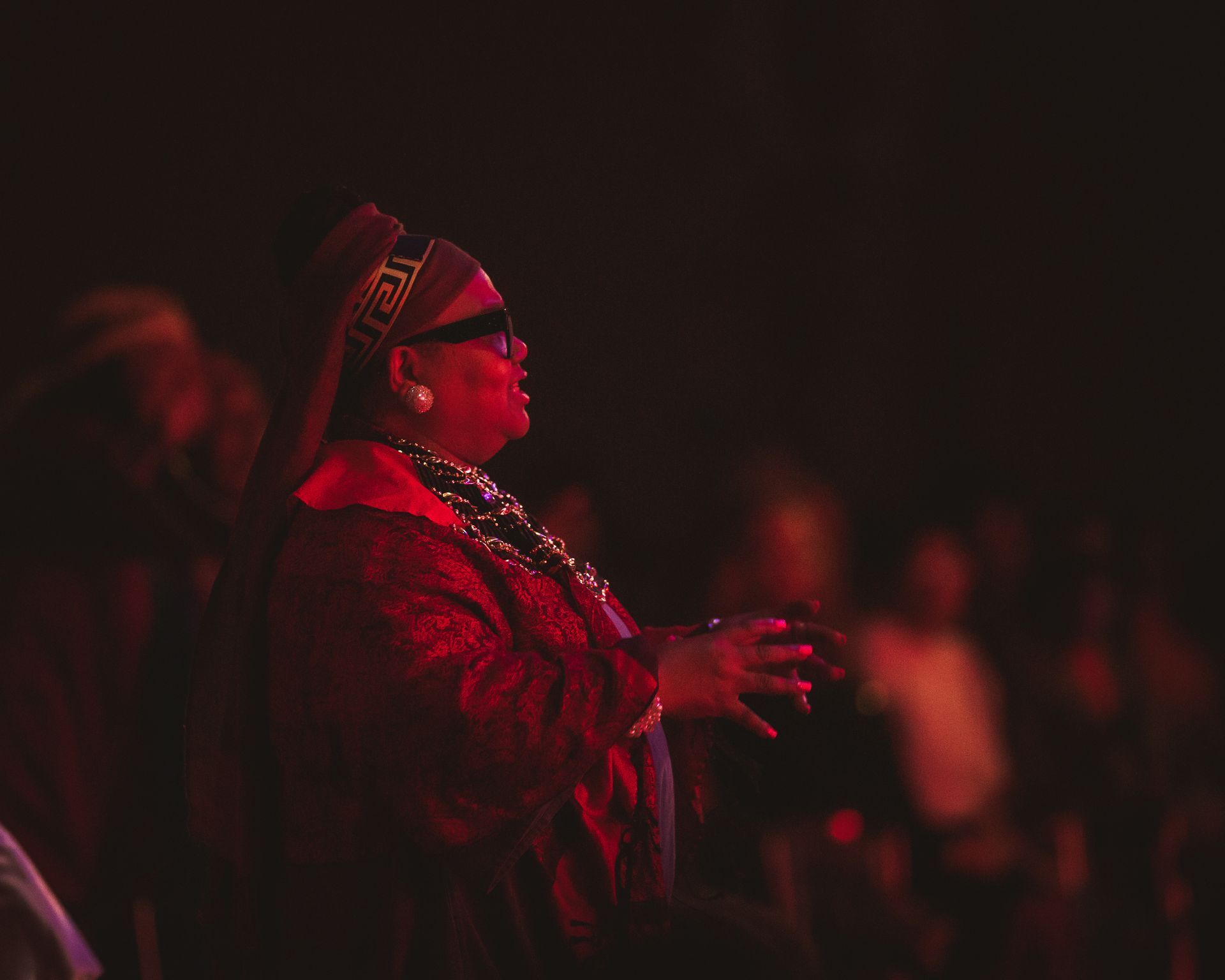 A woman is standing in a dark room with her hands in the air.