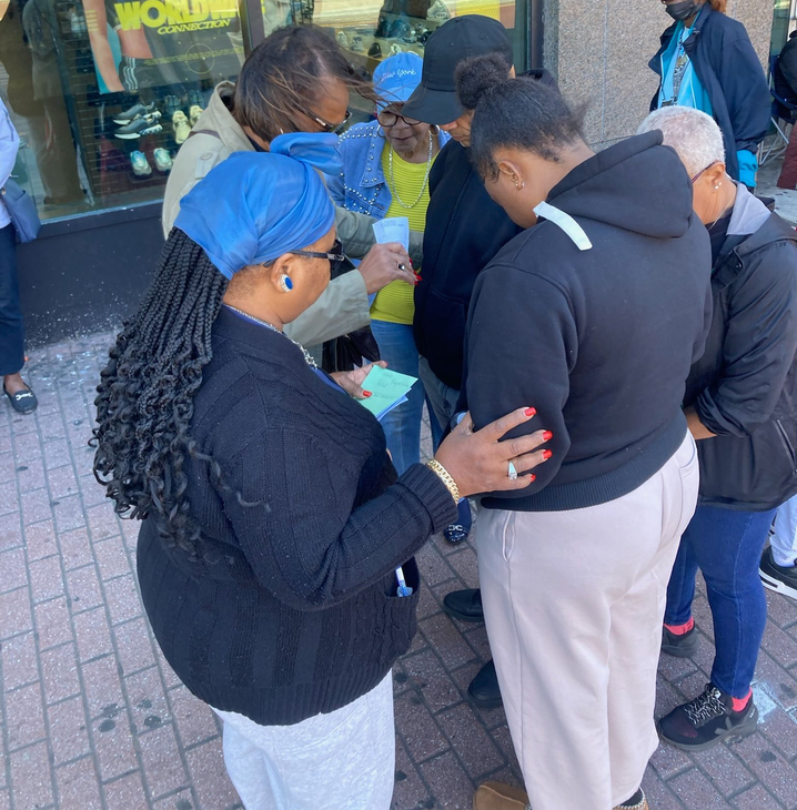 A cross sits amidst a colorful bouquet of flowers against a red background, with text reading: