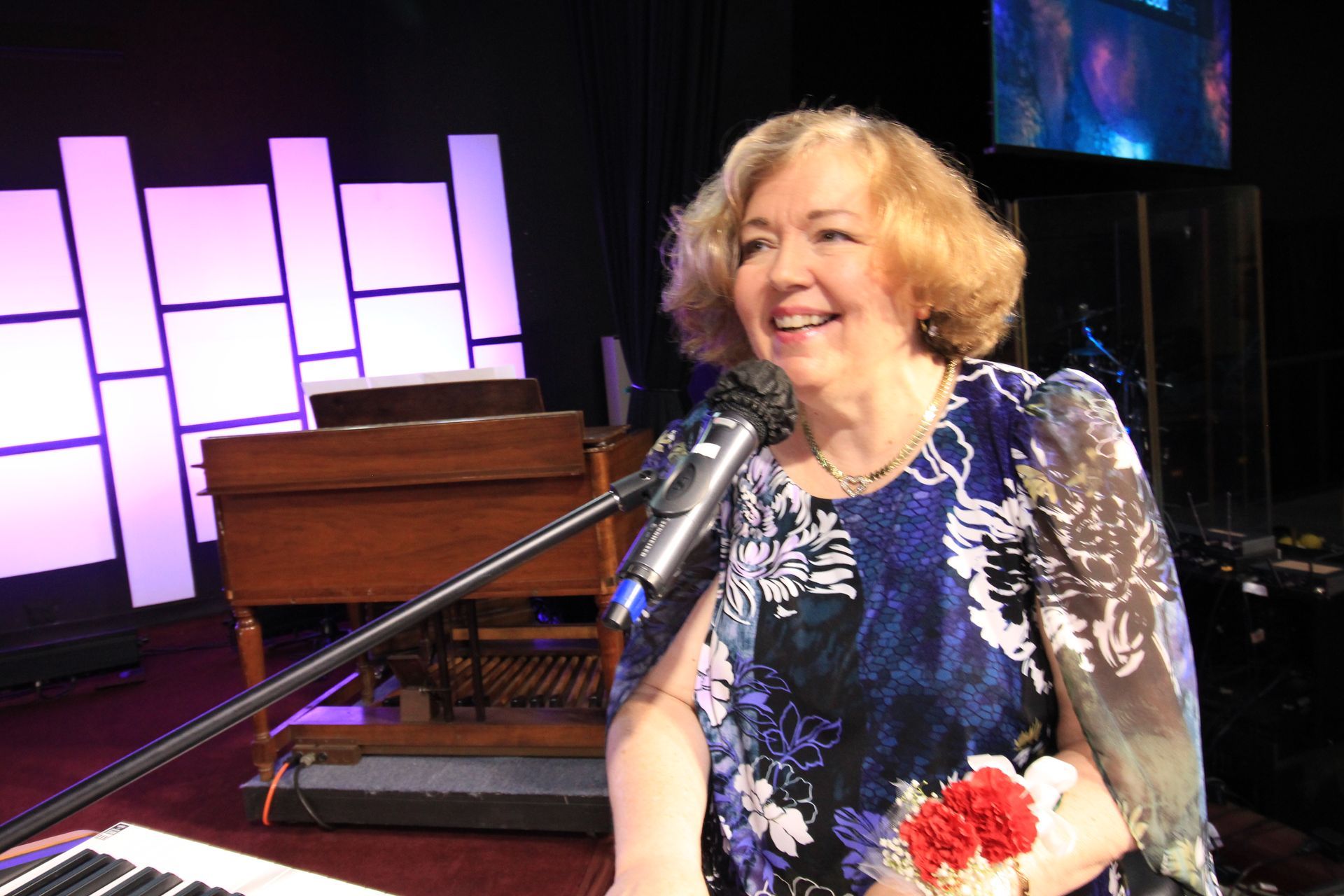 a woman in a blue dress is singing into a microphone on a stage .