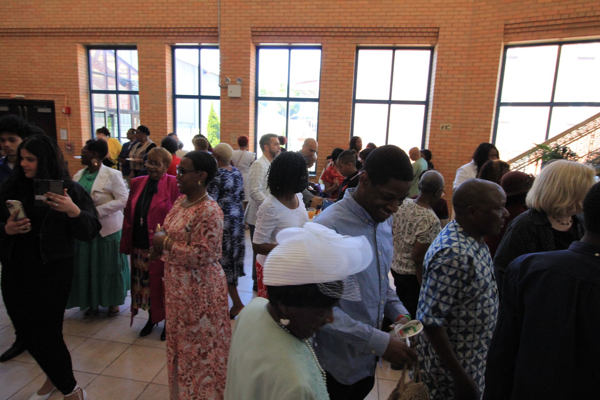 a group of people are standing in a room with a lot of windows .
