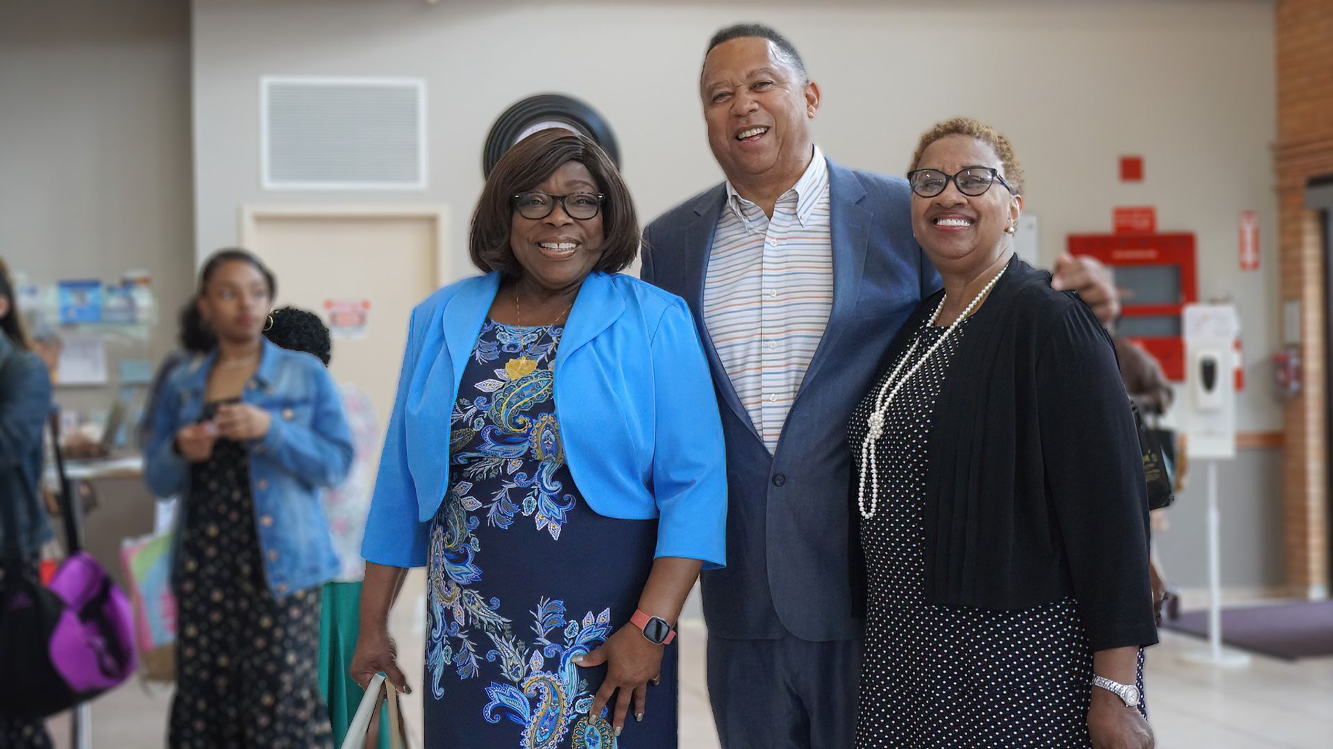 A man and two women are posing for a picture in a hallway.