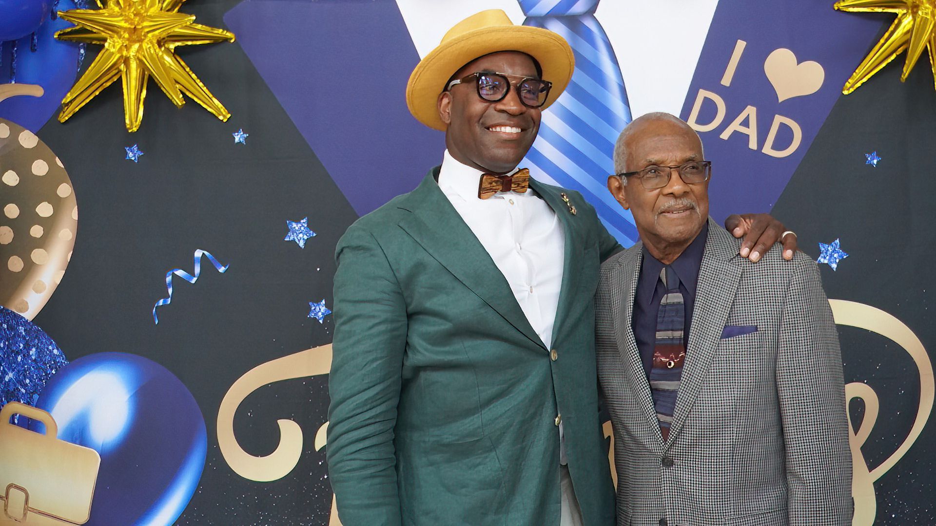 Two men are standing next to each other in front of a wall that says `` i love dad ''.
