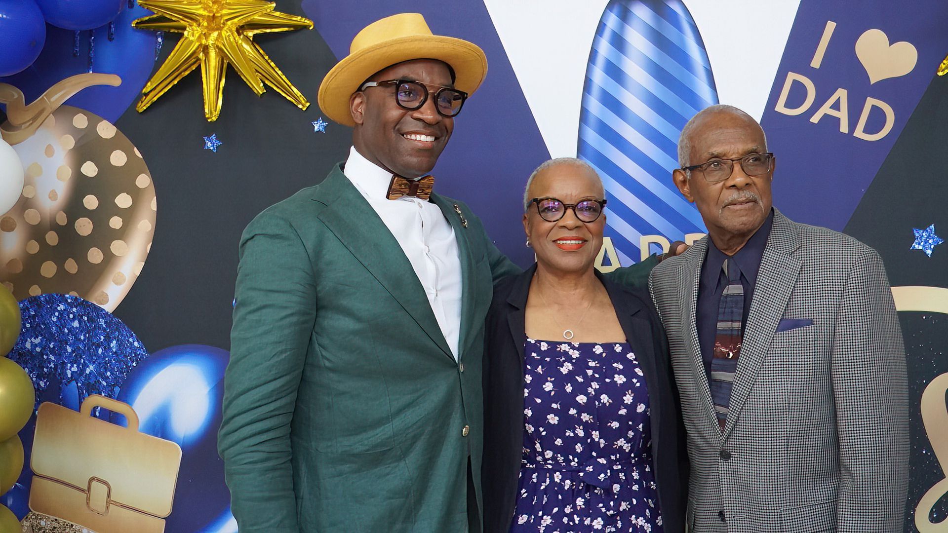 A man in a green suit is posing for a picture with his parents.