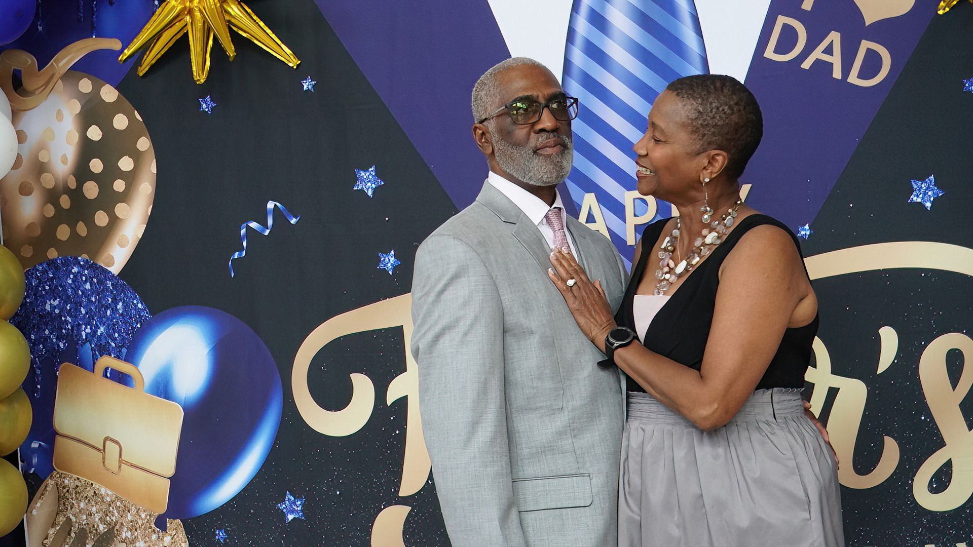 A man and a woman are posing for a picture in front of a backdrop that says dad