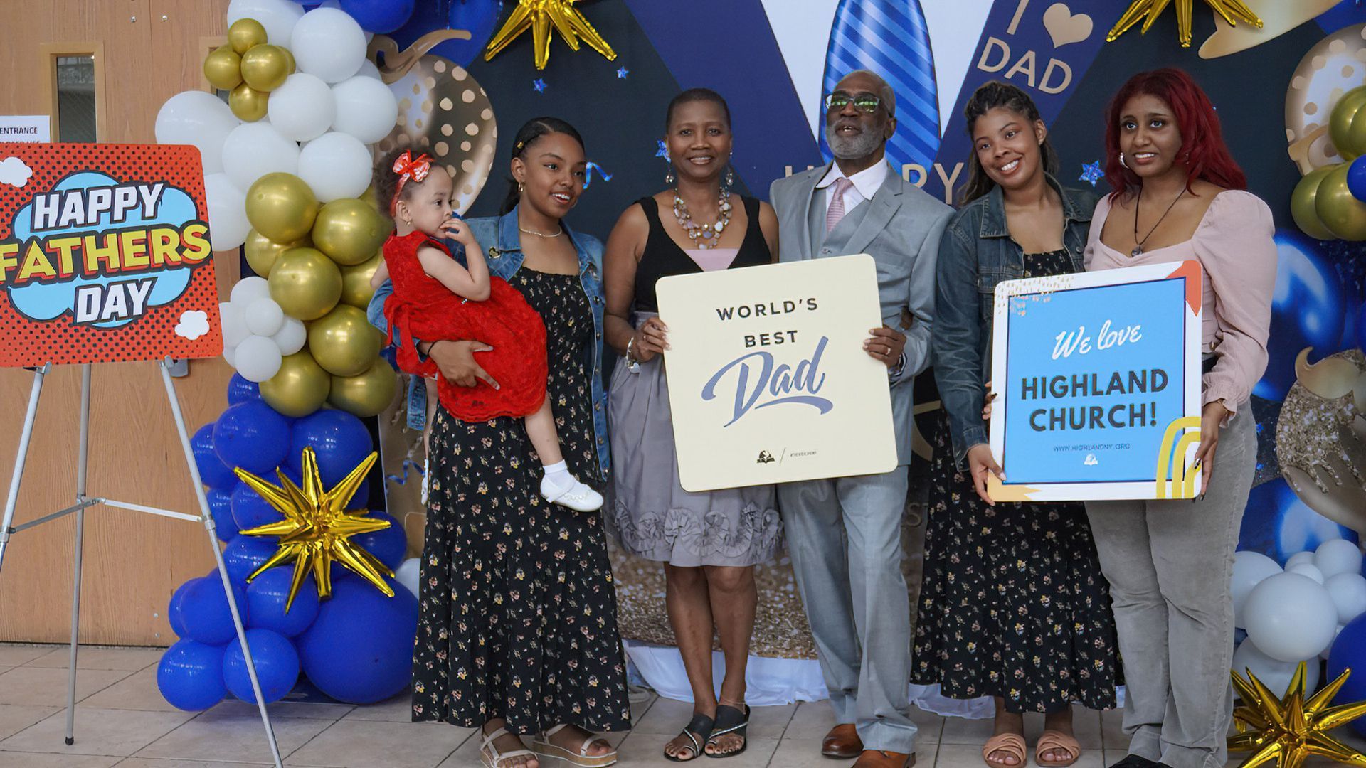 A group of people standing in front of a sign that says happy father 's day.
