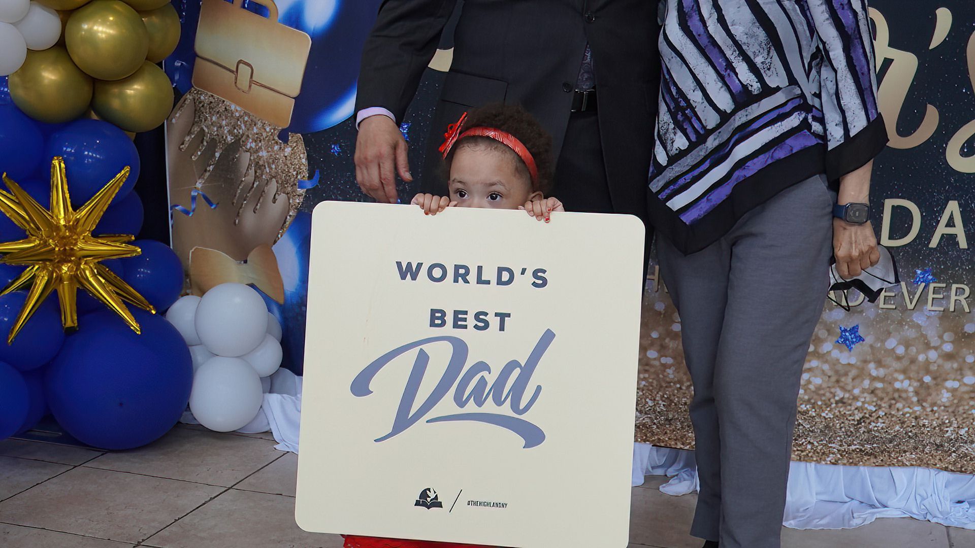 A little girl is holding a sign that says world 's best dad