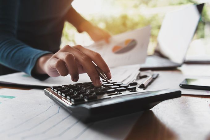 close up hand of business woman using calculator for working in office