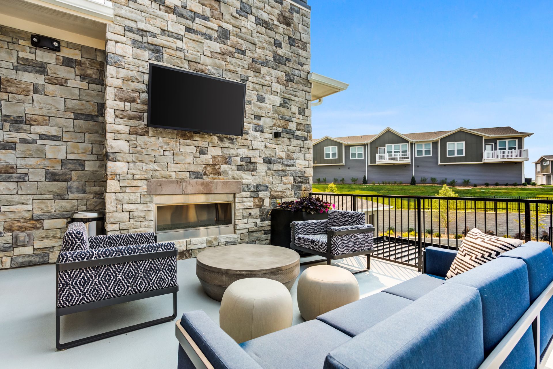 Blue playground slides on brown mulch, with houses in the background under a blue sky.