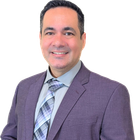 Edgardo in purple suit, light blue shirt, and patterned tie smiling, headshot.