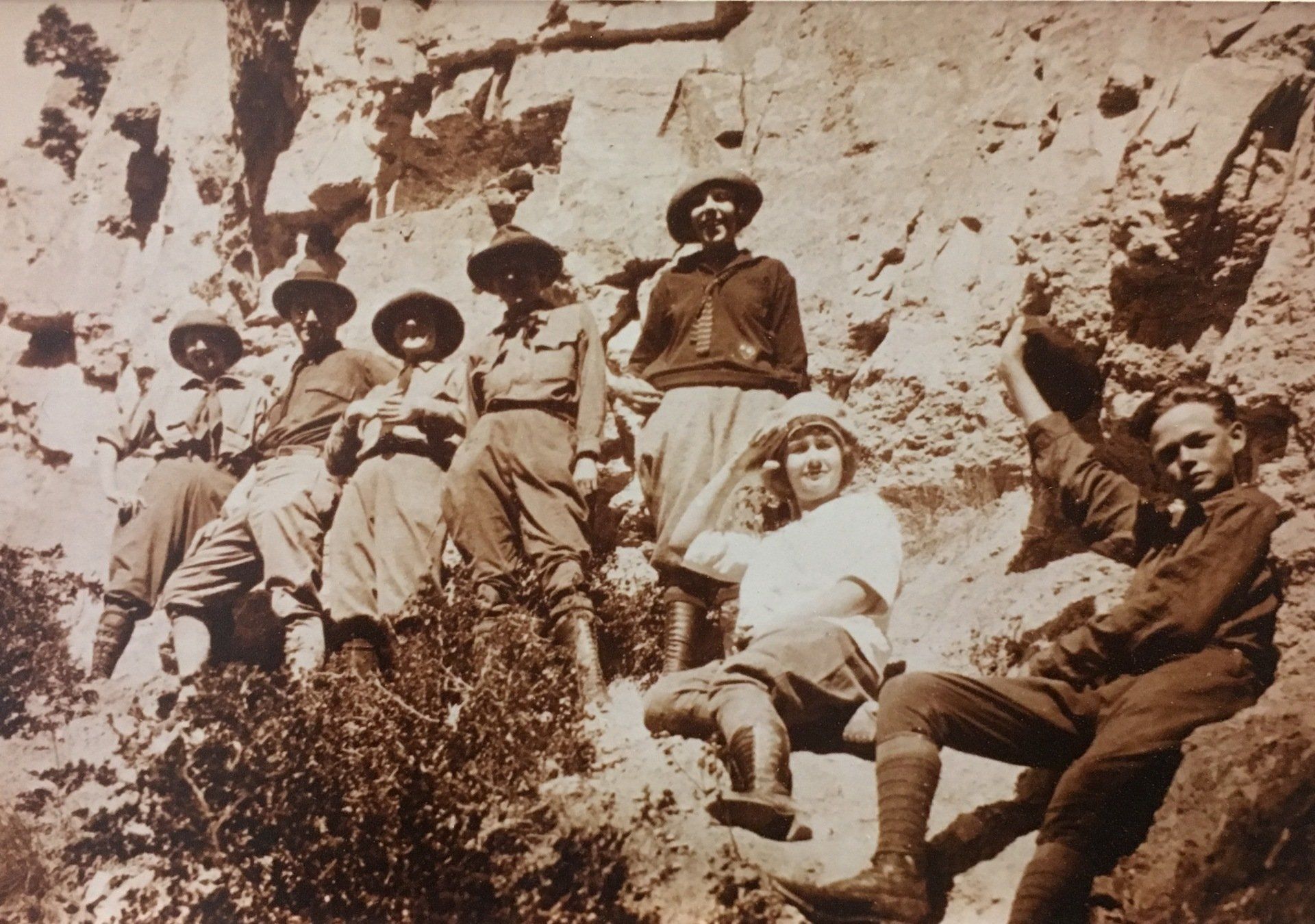 Group of people in period clothing pose on a rocky hillside.