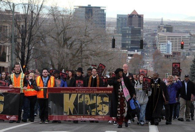 MLK Day parade in a city. Marchers carry a banner with