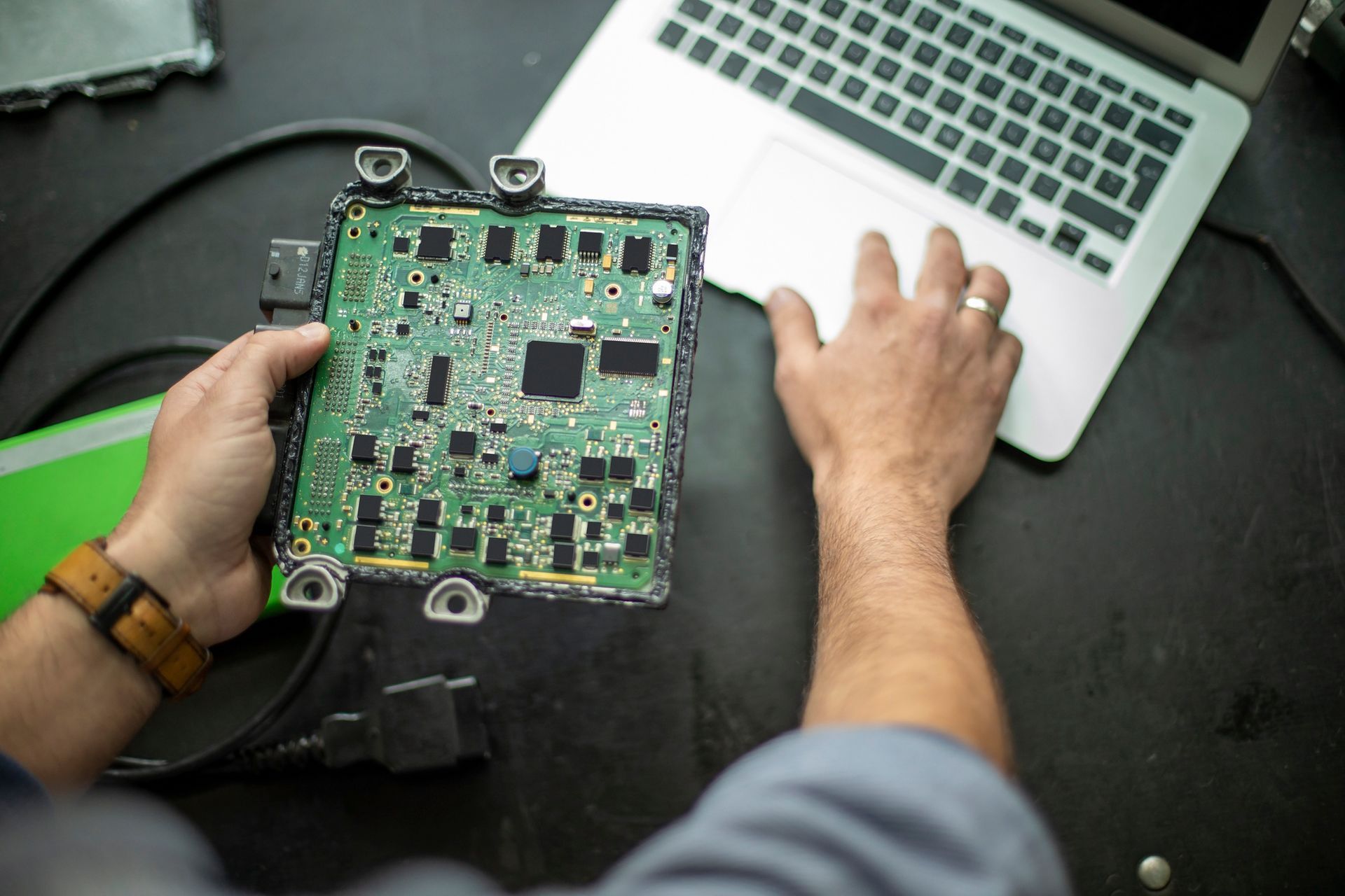 A man is holding a motherboard in front of a laptop.
