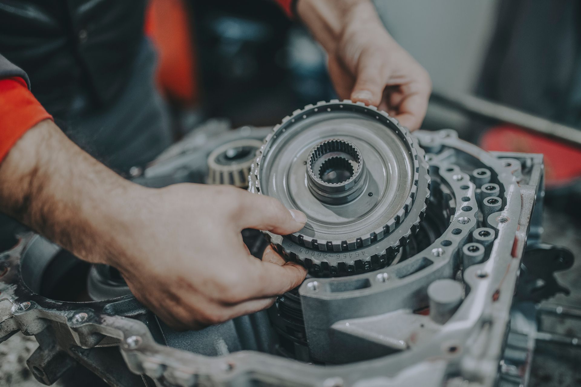A man is working on a gearbox in a garage.