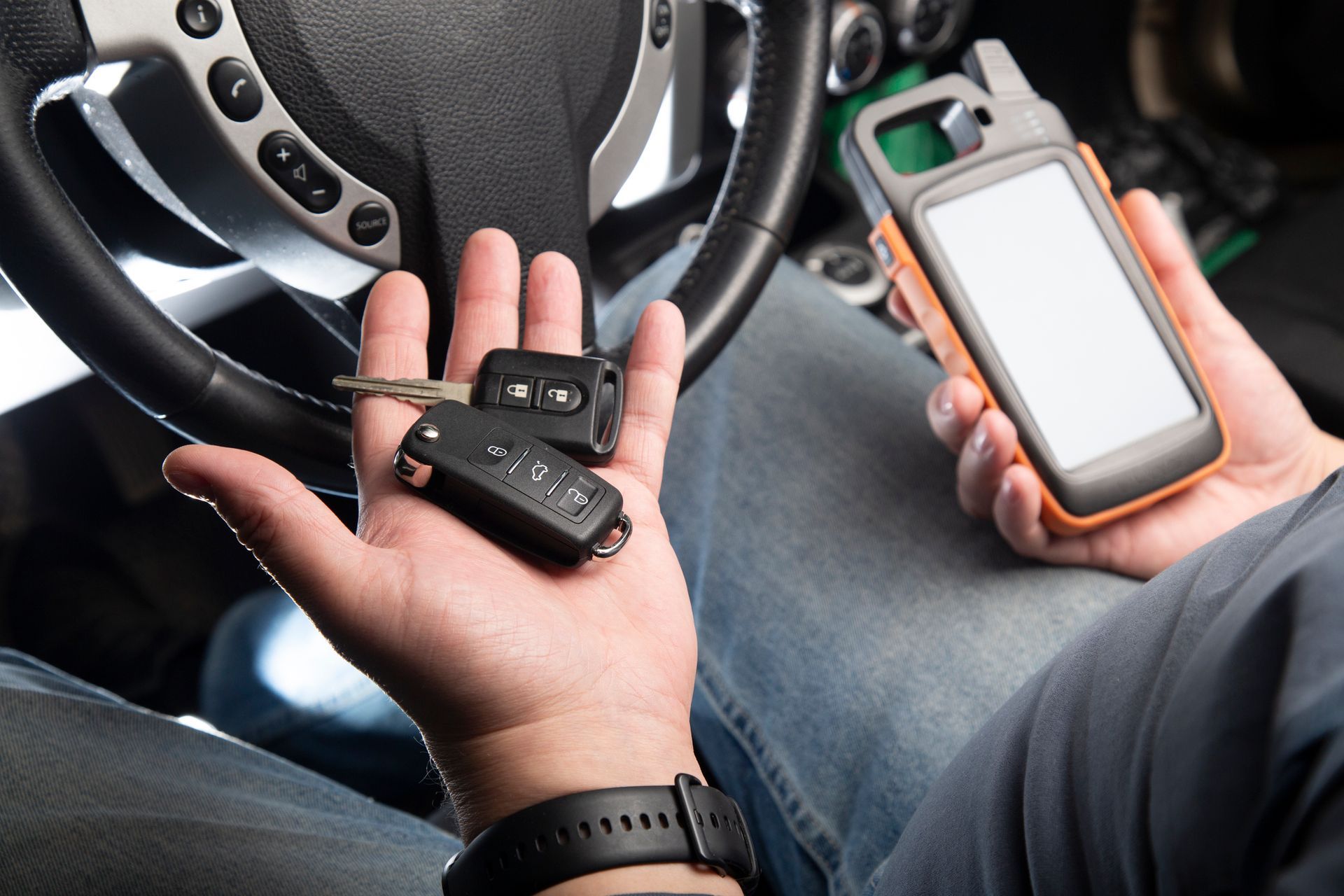 A person is holding a car key in their hand while sitting in a car.