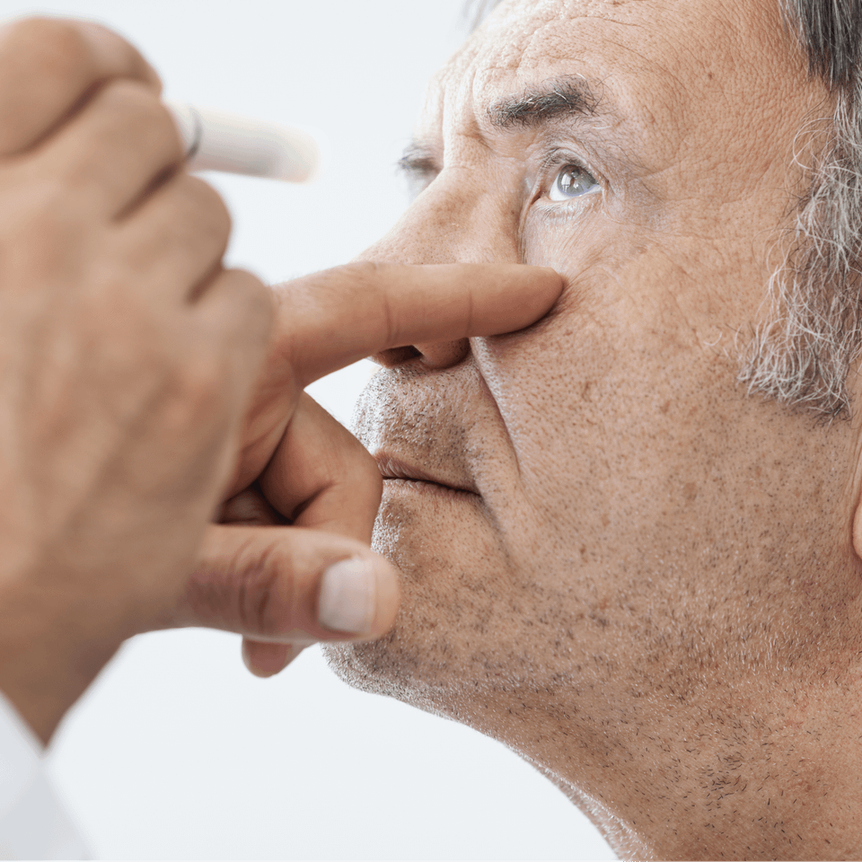 A man is applying eye drops to his eye