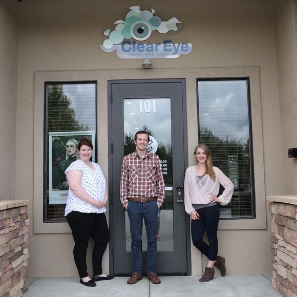 Three people standing in front of a clear eye store