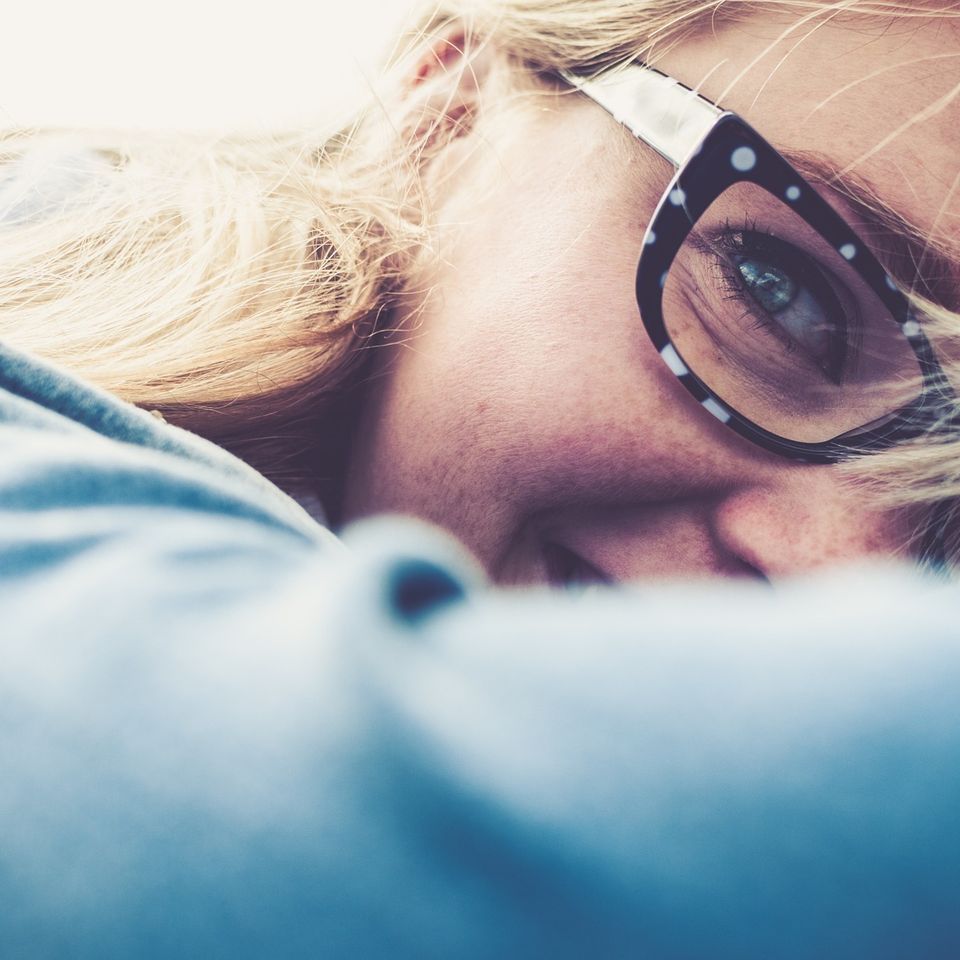 A close up of a woman wearing glasses and a blue shirt