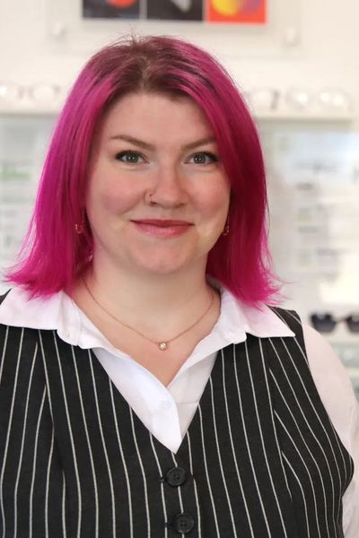 A woman with pink hair is wearing a black and white striped vest