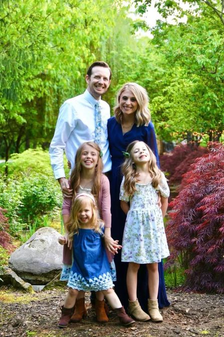 A family is posing for a picture in a park.