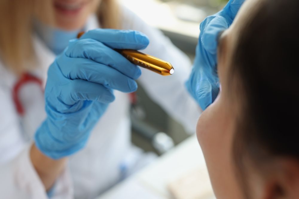 A doctor is holding a pen in front of a patient 's face.