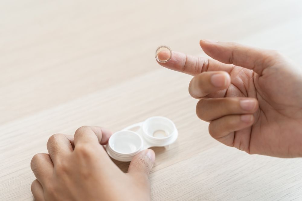 A person is pointing at a contact lens on their finger.