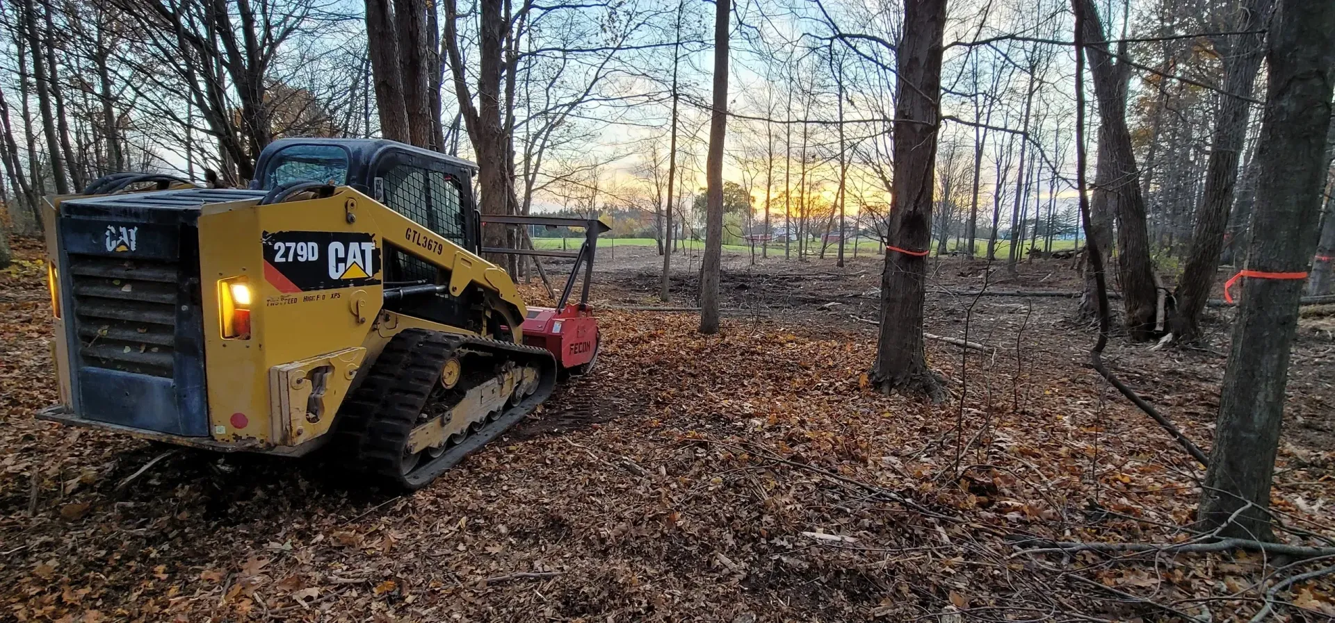 a bulldozer is driving down a dirt road with trees in the background