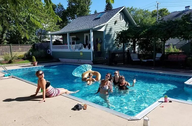 People in a pool near a house on a sunny day.
