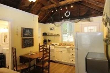 Small kitchen with wood ceiling, white cabinets, dining table, and refrigerator.