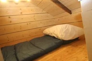 Sleeping bag and pillow in a small, wooden attic room.