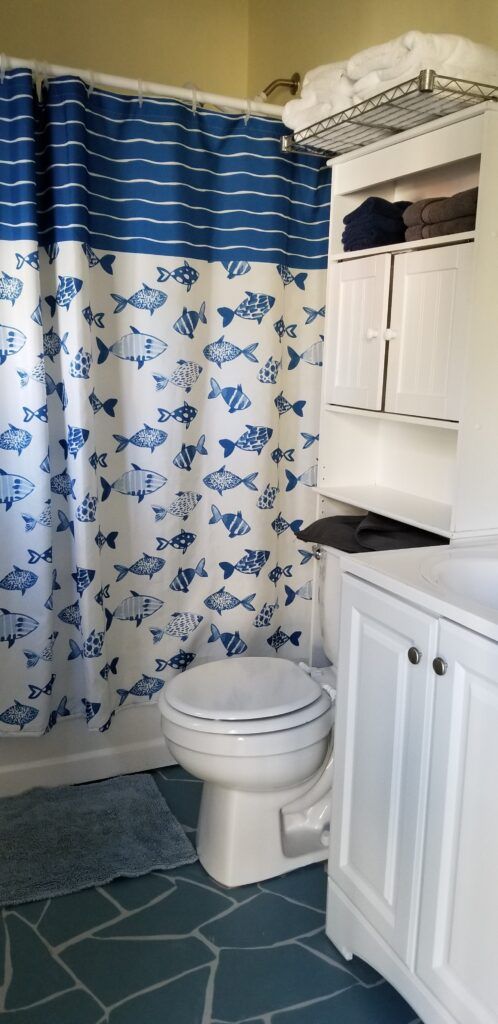 A small bathroom with a fish-patterned shower curtain.