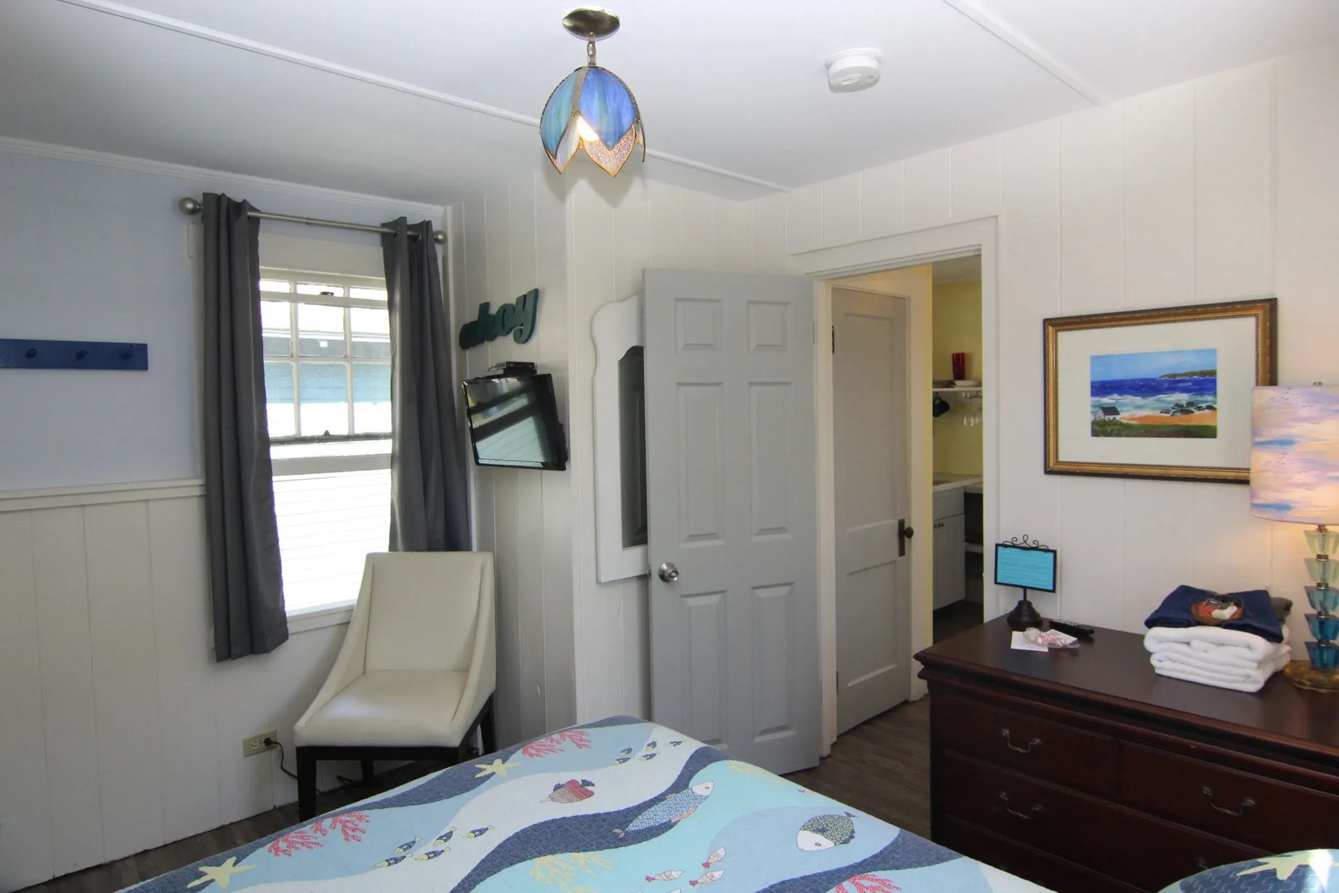 Bedroom with a bed, chair, window, dresser, and open doorway. 