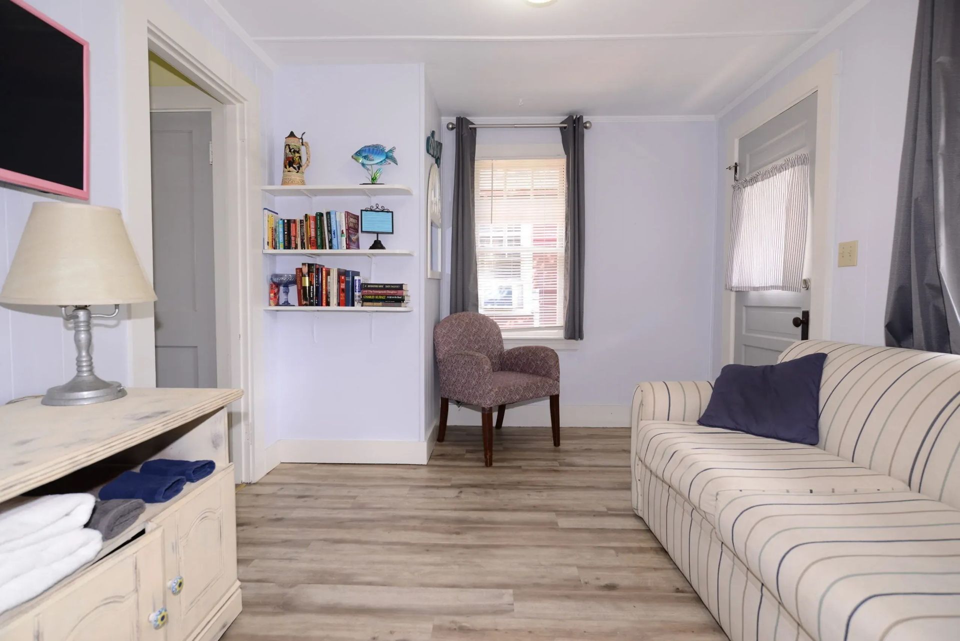 Living room with a sofa, chair, bookcase, window, and doorway. 